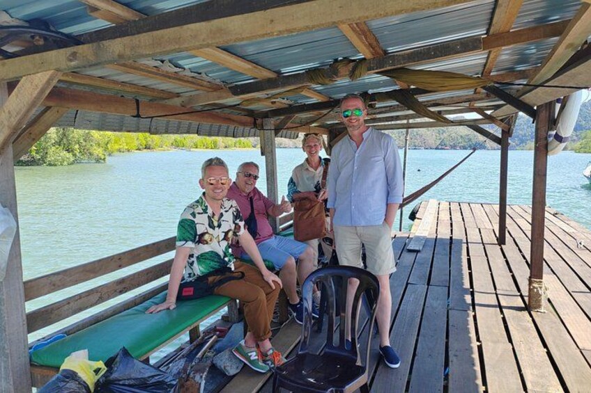 A wooden dock with people sitting and standing, overlooking a body of water. 2