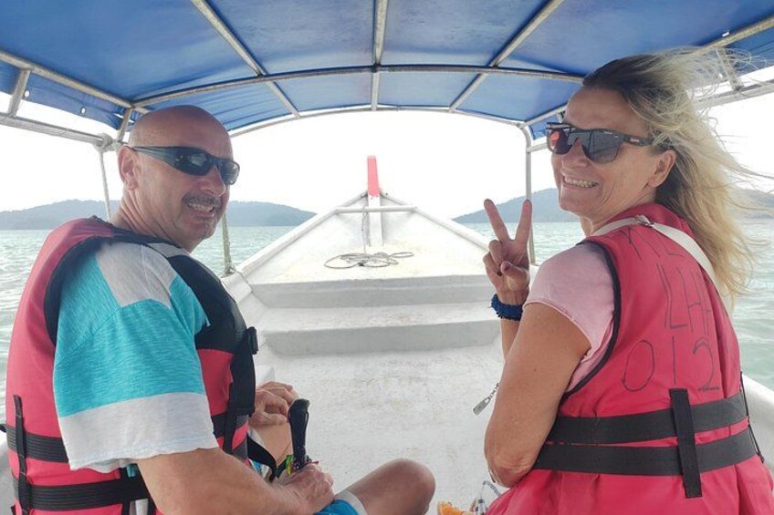 Two people on a boat wearing life jackets, with water and a distant landmass in the background. 4