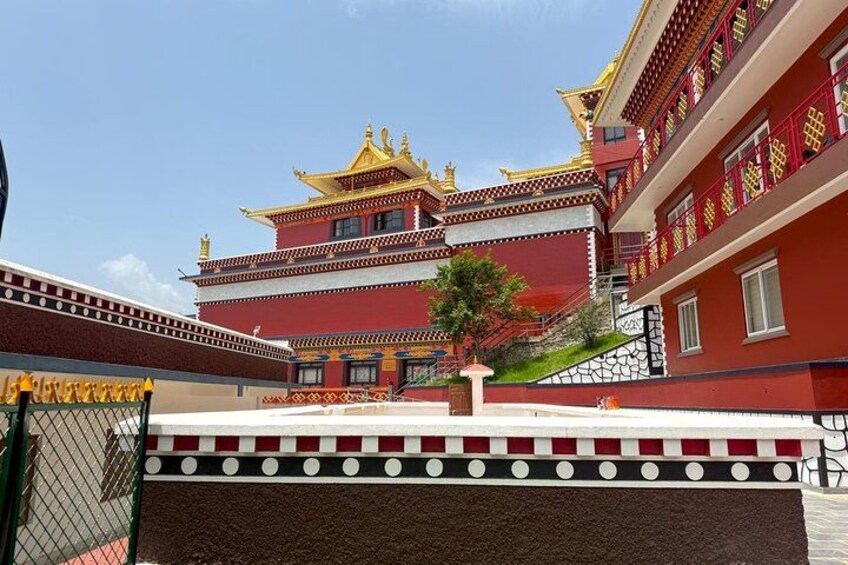 A traditional multi-tiered building with red and gold accents, a small tree, and a clear blue sky. 4