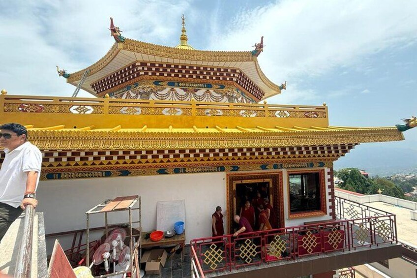 A traditional temple with ornate architecture, a red railing, and a person standing on the balcony. 2