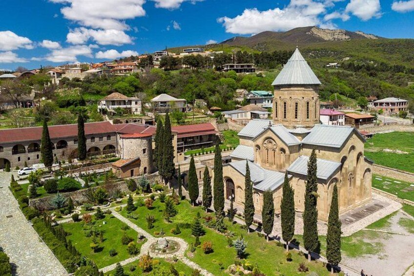 Une église historique dotée d’un clocher, entourée d’un jardin bien entretenu et de bâtiments résidentiels dans une ville située sur une colline. 2