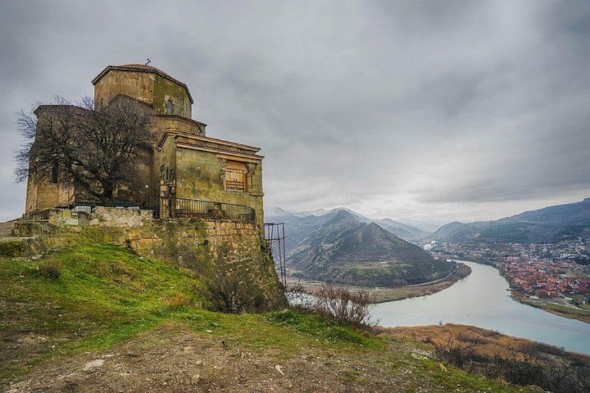 Un bâtiment historique situé sur une colline, d’où l’on a une vue sur une rivière et des montagnes. 4