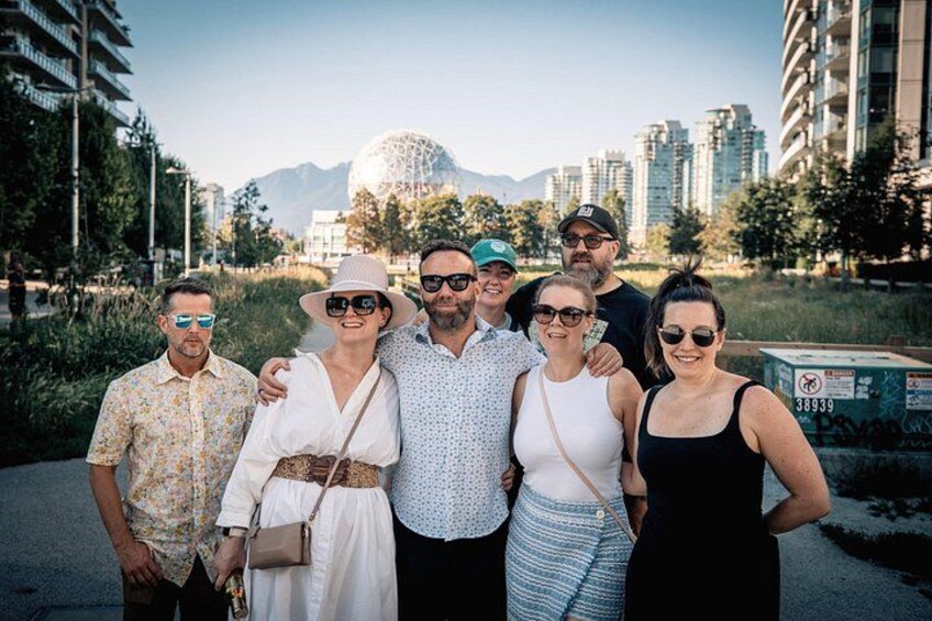 A group of people standing in a park with buildings and mountains in the background. 2