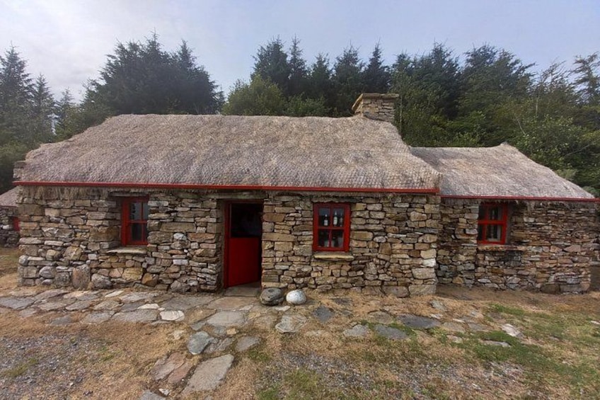 A stone house with a thatched roof and red trim. 5