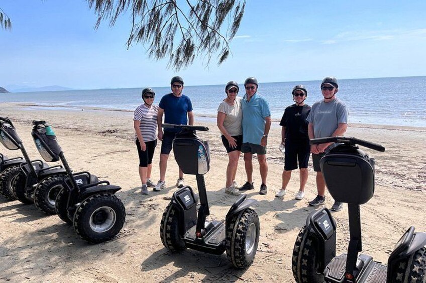 A group of people on a beach with several Segways. 4