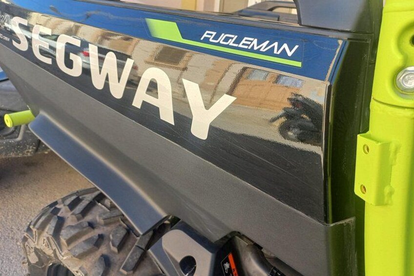 A vehicle with 'SEGWAY' and 'FUGLEMAN' branding, a green handlebar, and a black and green body. 2