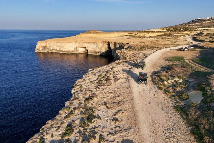 A coastal road with vehicles, cliffs, and the sea. 5