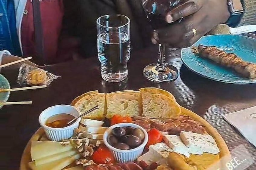 Una comida con pan, queso, aceitunas y una bebida. 4