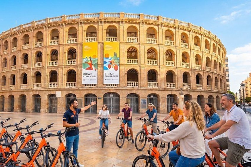 Un grupo de personas en bicicletas frente a un edificio histórico con arcos. 3