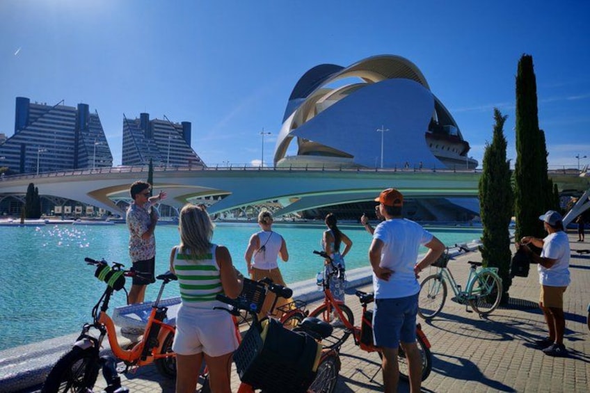 Una orilla con gente, bicicletas y un edificio moderno distintivo. 2