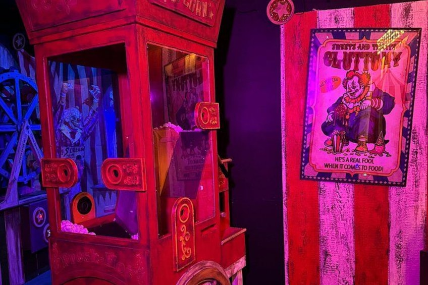 A vintage-style candy machine with a clown illustration and a sign that reads 'Sweets and Ties Gluttony.' 3