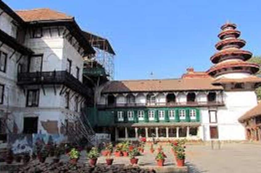 A traditional building with a multi-tiered pagoda-like structure, surrounded by potted plants and a clear blue sky. 2