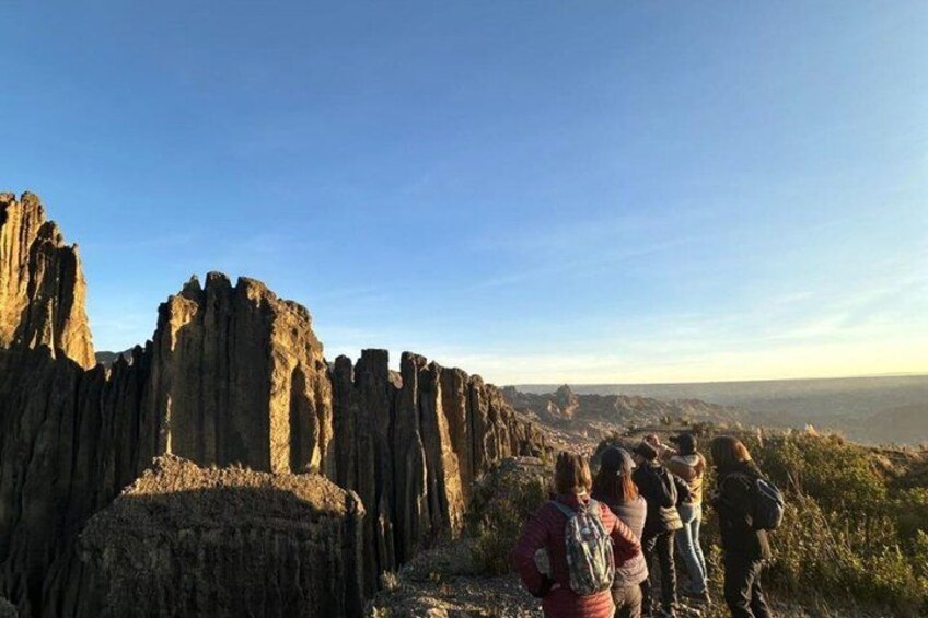 A group of people standing on a rocky outcrop overlooking a vast landscape with tall, narrow rock formations. 5
