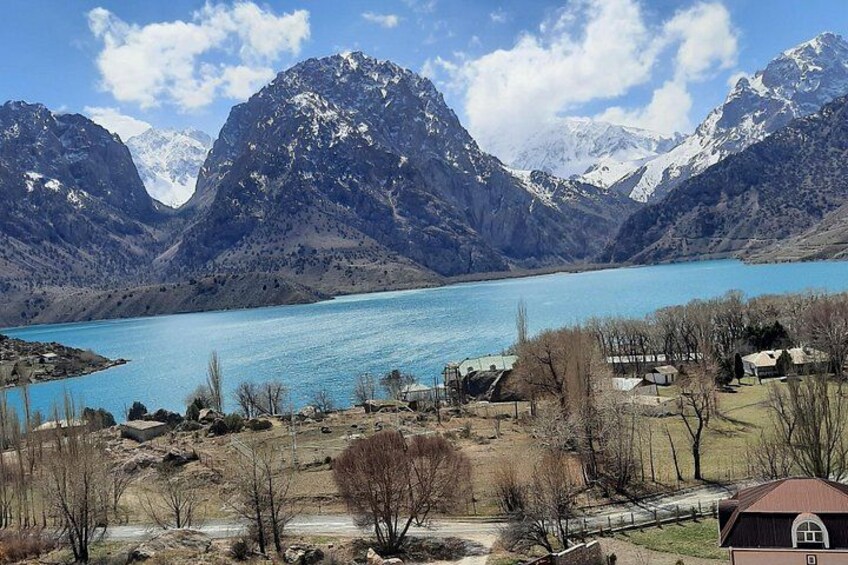 Paesaggio montuoso con un lago, alcune case e cielo sereno. 3