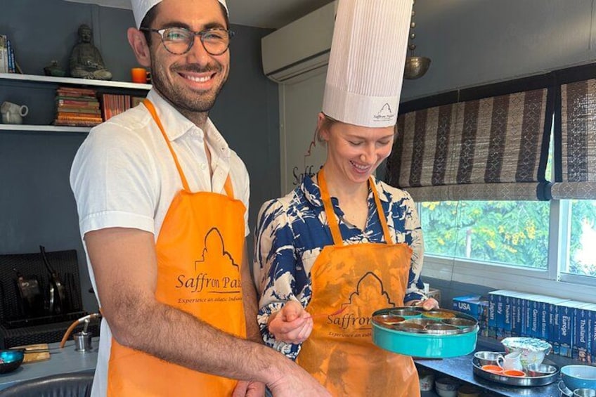 Twee personen in een keuken, gekleed in schorten met het Saffron Paris logo. 3