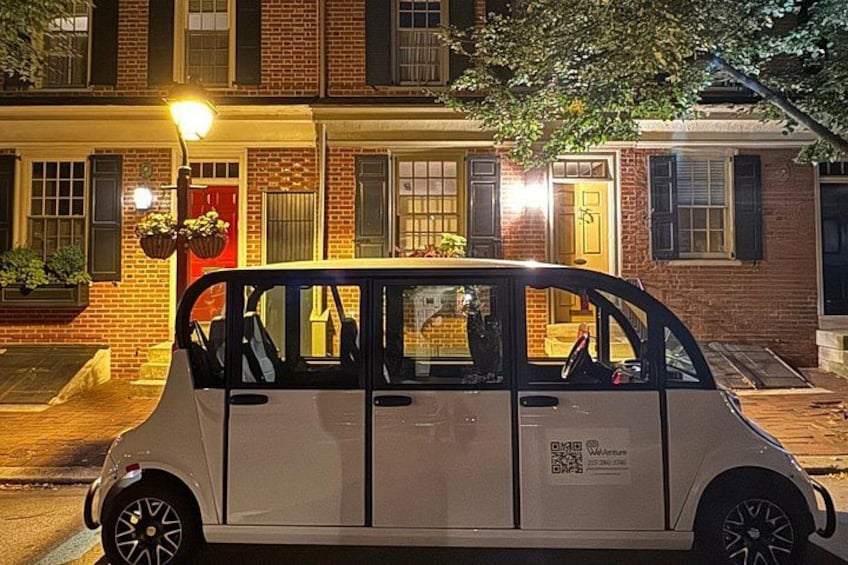 A white car parked on a street at night with a QR code on the side. 1