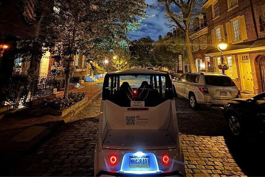 A white van parked on a cobblestone street at night. 5