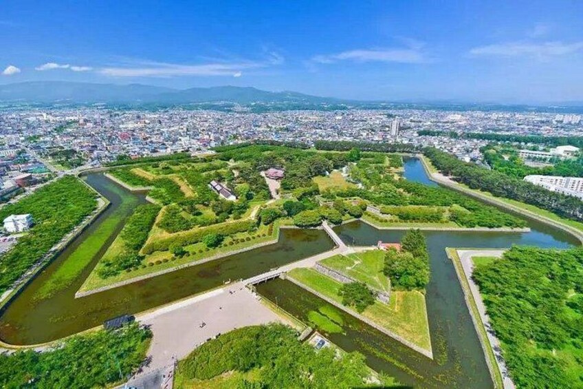 A river meandering through a park with green areas and a cityscape in the background. 5