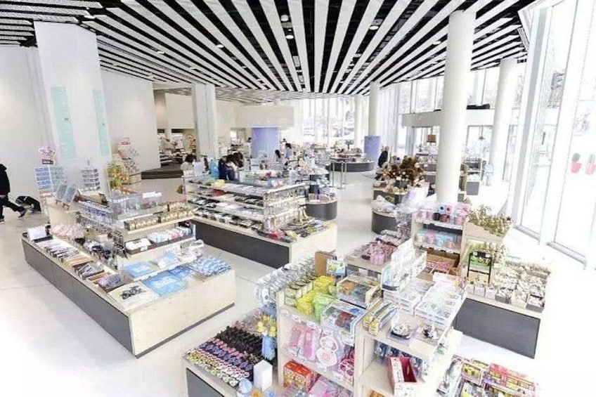 A spacious indoor market with various stalls selling books, magazines, and stationery. 3