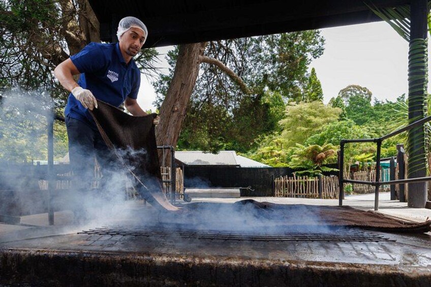 A person grilling outdoors with smoke rising, surrounded by trees and a wooden fence. 3