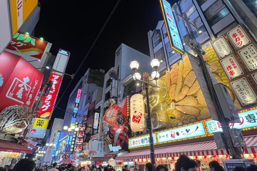 A busy urban street at night with illuminated signs and billboards. 2