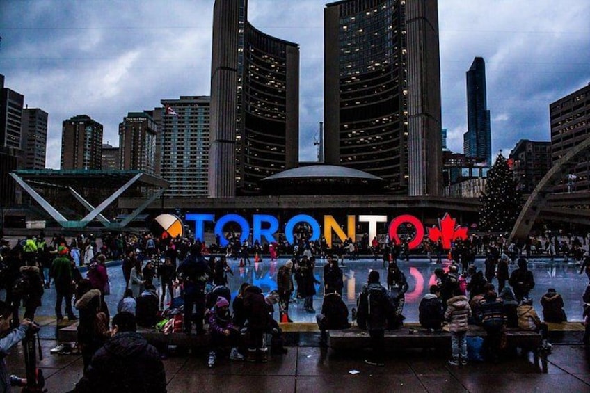 Une place animée où se trouve l’enseigne « Toronto », entourée de grands immeubles. 2