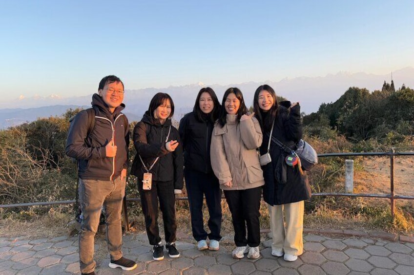 A group of people standing on a paved path with a mountainous landscape in the background. 5