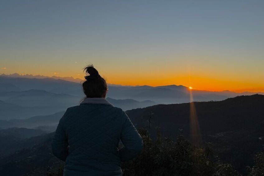 A person standing on a hill overlooking a mountain range during sunset. 1