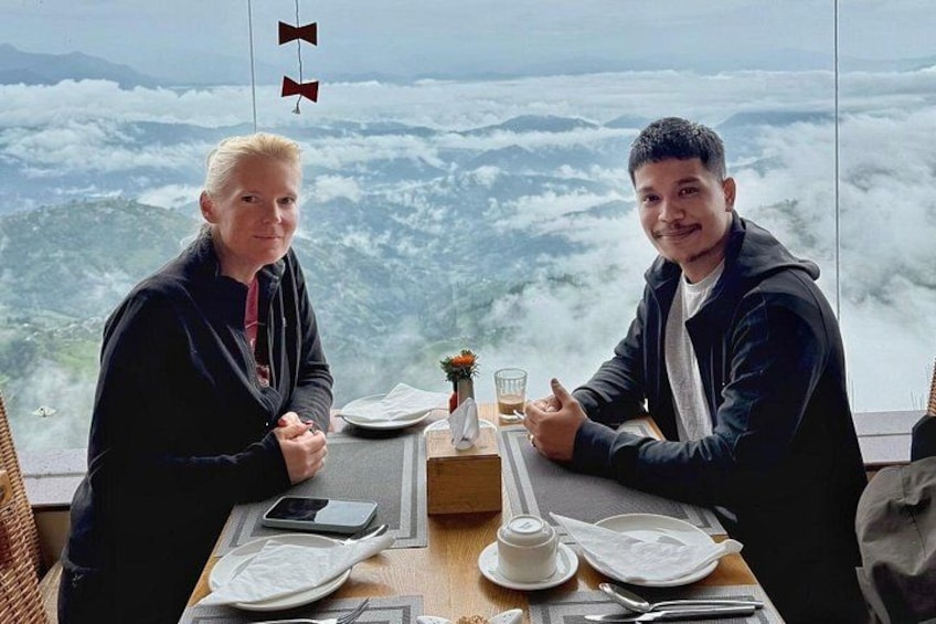 Two people sitting at a table with a mountain view. 3