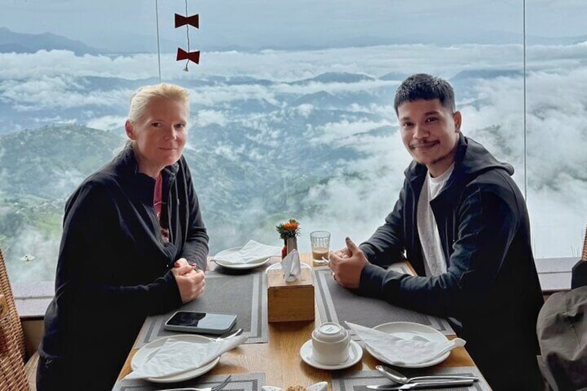 Two people sitting at a table with a mountain view. 3