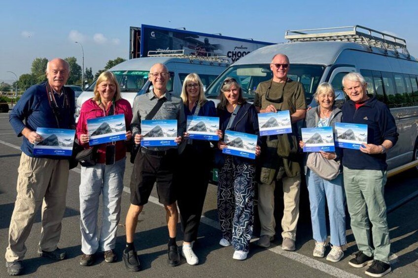 A group of people holding brochures in front of a vehicle. 3