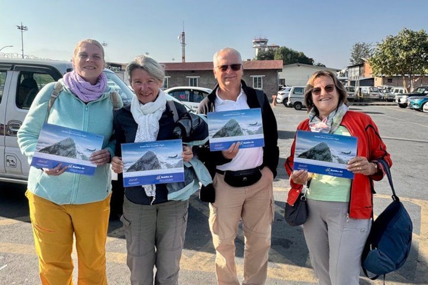 Four people holding books with mountain landscapes on the cover. 2