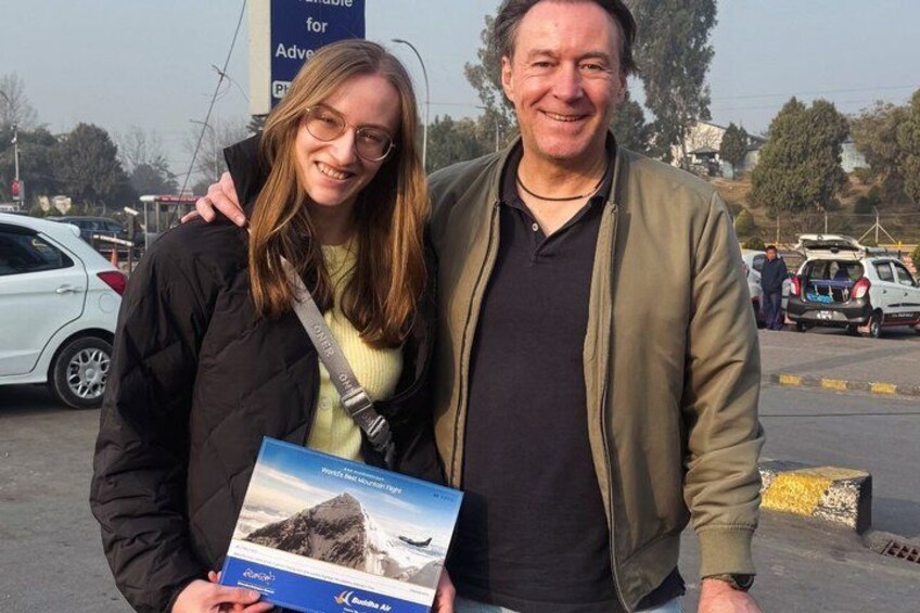 Two people standing in a parking lot with a sign in the background. 4