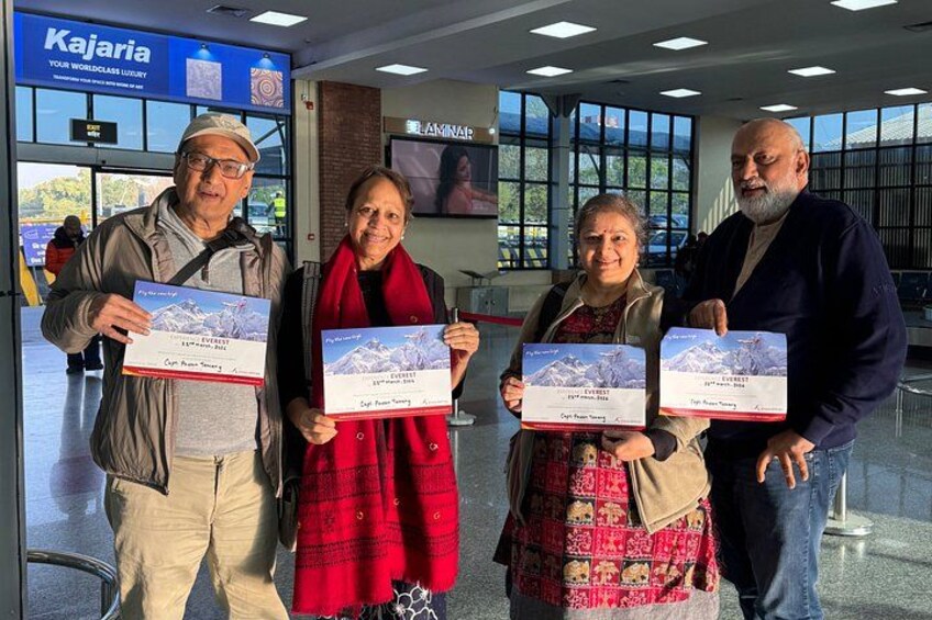 Four people holding certificates in a building with a sign that reads 'Kajaria.' 4
