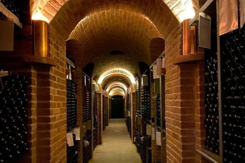 A wine cellar with brick walls and rows of wine bottles. 3