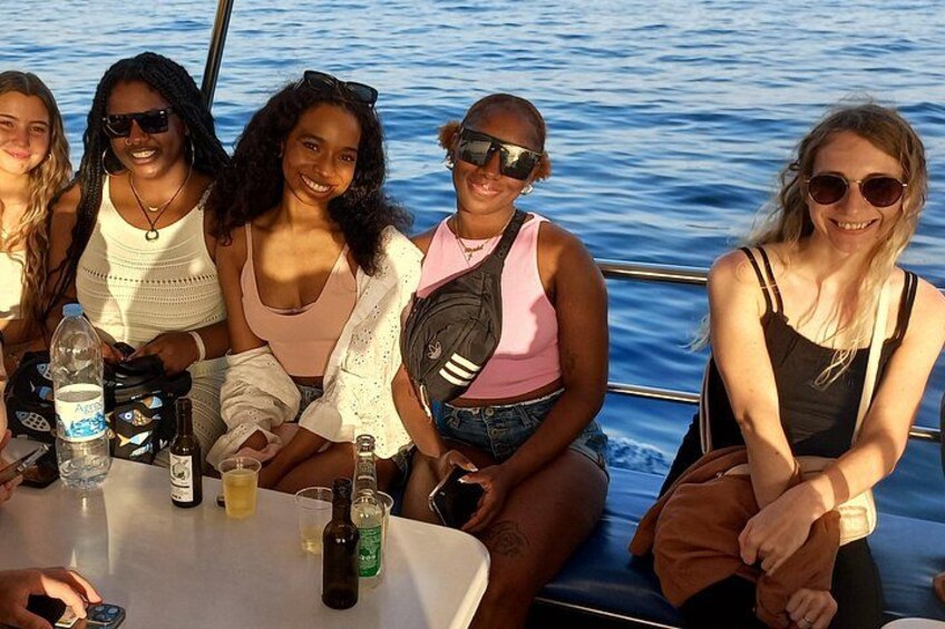A group of people on a boat with bottles and a glass of water on the table. 3
