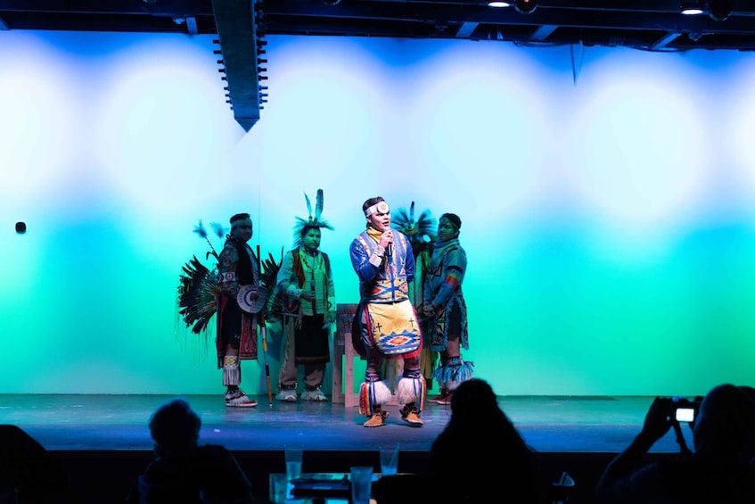 Eine Bühnenaufführung mit Schauspielern in traditioneller Tracht und Federkopfschmuck. 5