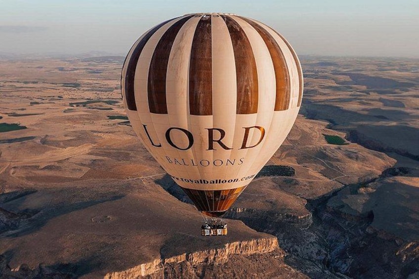 Un globo aerostático con la leyenda 'LORD BALLOONS' volando sobre un paisaje desértico. 1