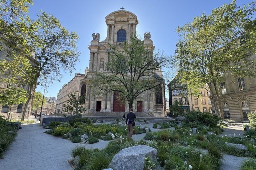 A historic church with a central dome and bell tower, surrounded by a landscaped garden with large rocks and trees. 5