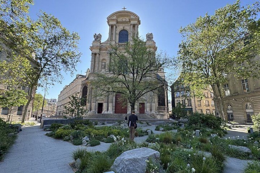 A historic church with a dome and bell tower, surrounded by a landscaped garden with large rocks and trees. 4