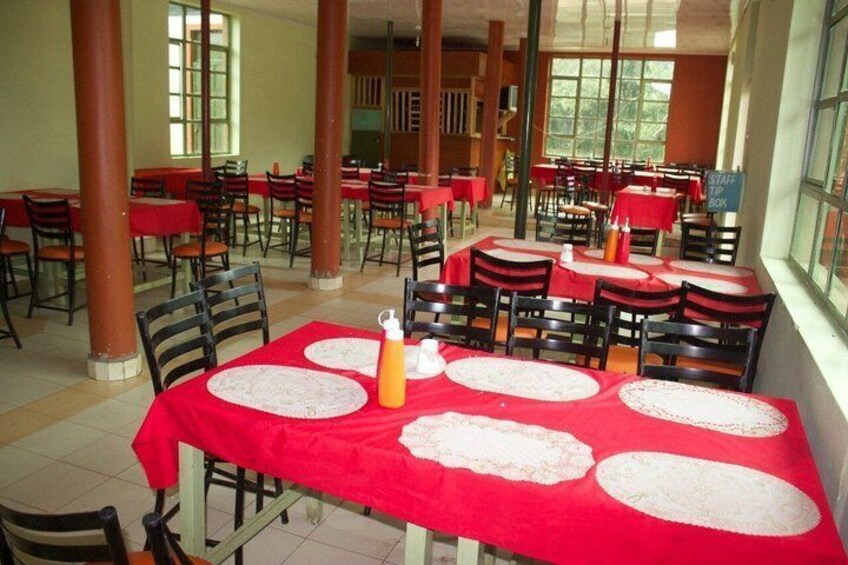 A dining area with tables covered in red tablecloths, white placemats, and orange condiment bottles. 3