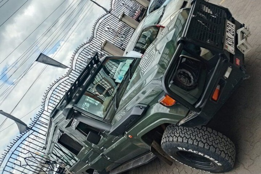 A green off-road vehicle with a spare tire and a license plate. 2