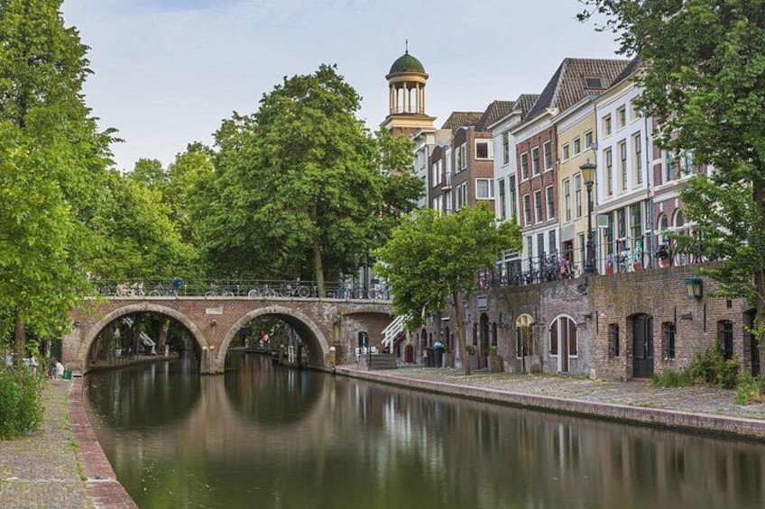 A canal with a bridge, trees, and historic buildings. 5