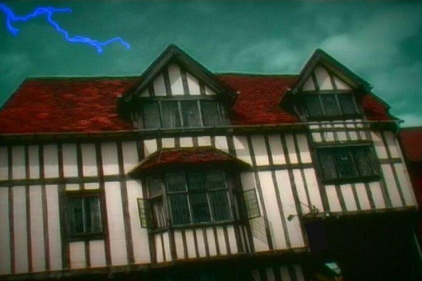 A Tudor-style house with a steeply pitched roof, white and dark timber framing, and a red-tiled roof. 2