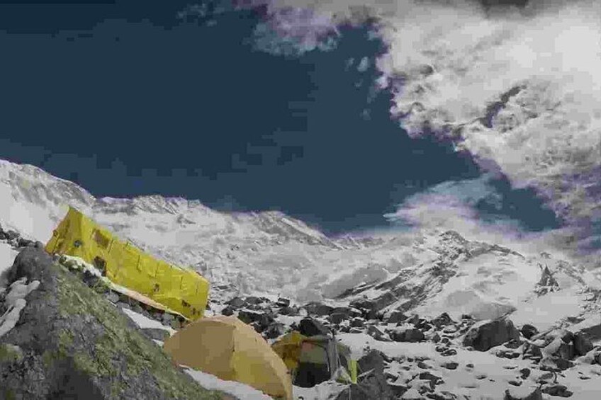 A snowy mountain landscape with a yellow tent and a rocky terrain. 3