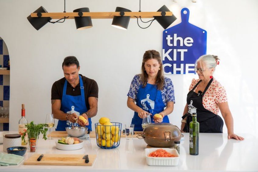 Tres personas preparando comida en una cocina con un letrero que dice 'the KIT CHEF'. 1