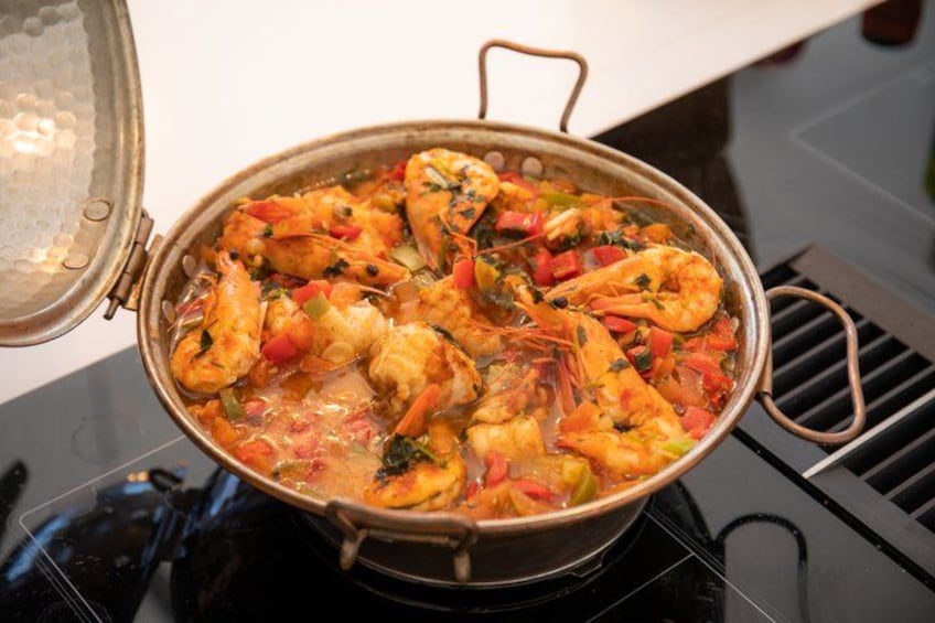 Una olla con camarones cocidos y verduras sobre una estufa. 3