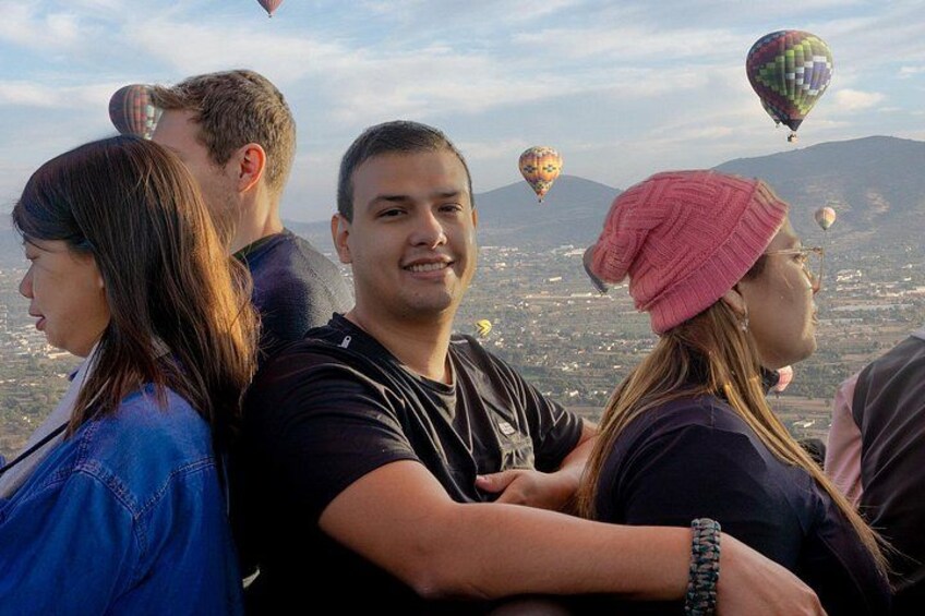 Un grupo de personas observando globos aerostáticos en una zona montañosa. 2