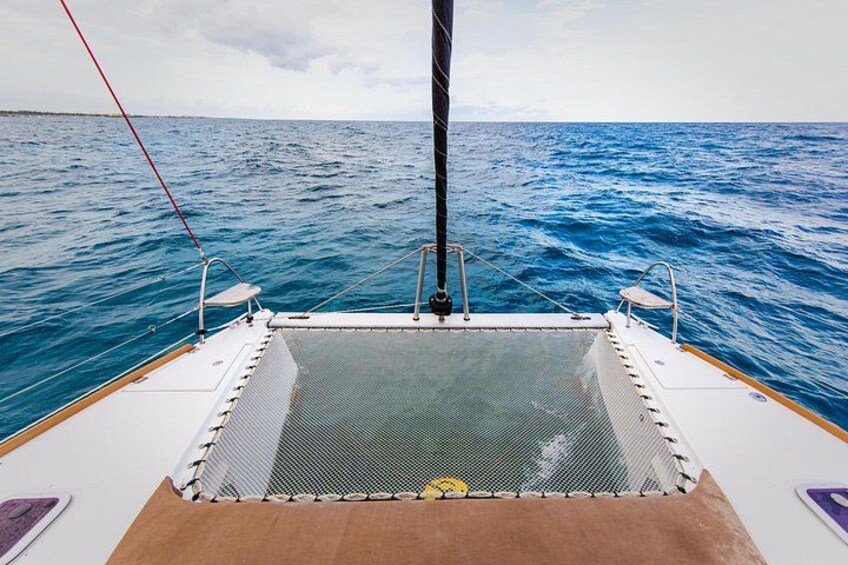 Ett båtdäck med ett område avgränsat av ett nät, en mast och havet i bakgrunden. 2