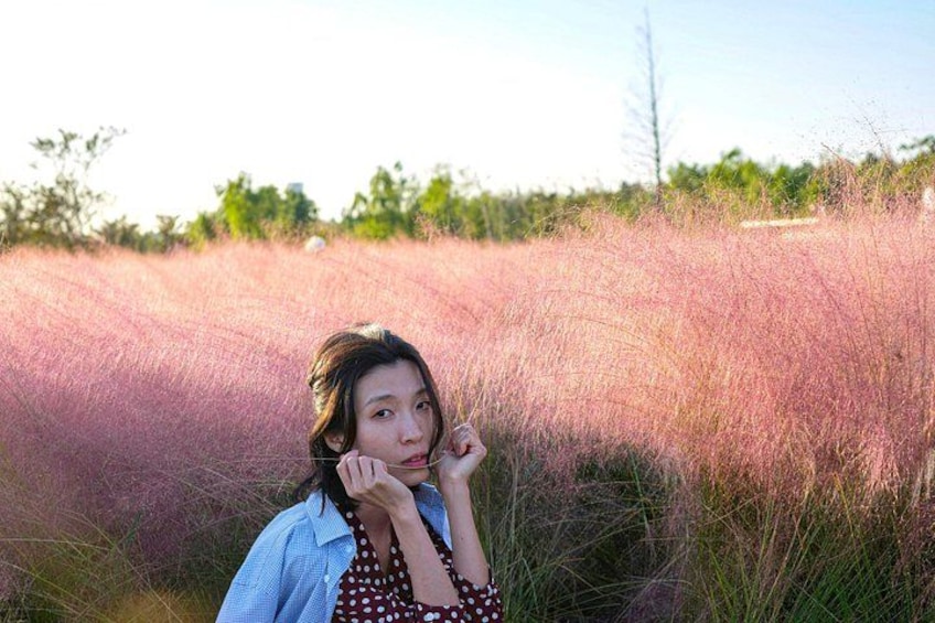 A person standing in a field of tall grass with a blue shirt and a polka dot dress. 4